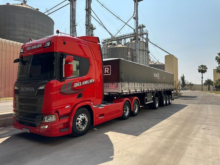 Scania vermelha da Delamura com graneleiro em frente aos silos